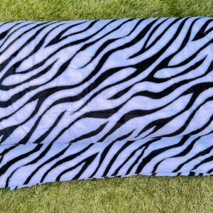Zebra patterned fleece throw blanket displayed on grass.
