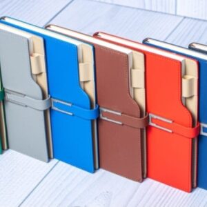 Seven colorful, closed, leather-bound planners with metal clasps (Green, Grey, Blue, Brown, Red, Navy, Charcoal).